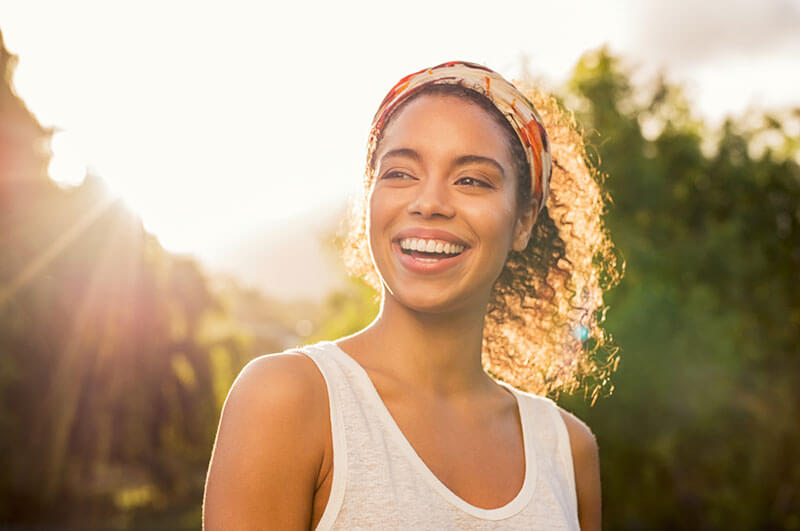 woman smiling with sunshine in the background