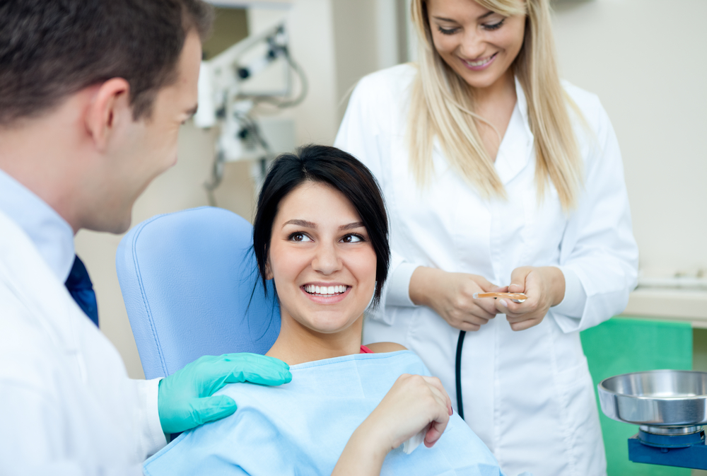 a young woman in the dental chair surrounded by dentists