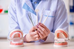 dentist holding dental tools in front of models of dentures