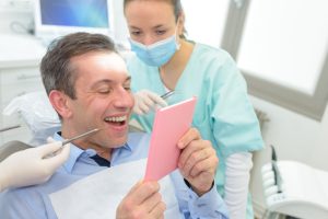 dentist showing patient his smile in a hand mirror