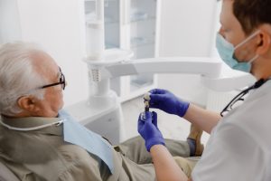 dentist showing older patient model of teeth