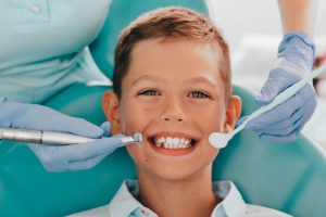 kid smiling while dentist examines his teeth